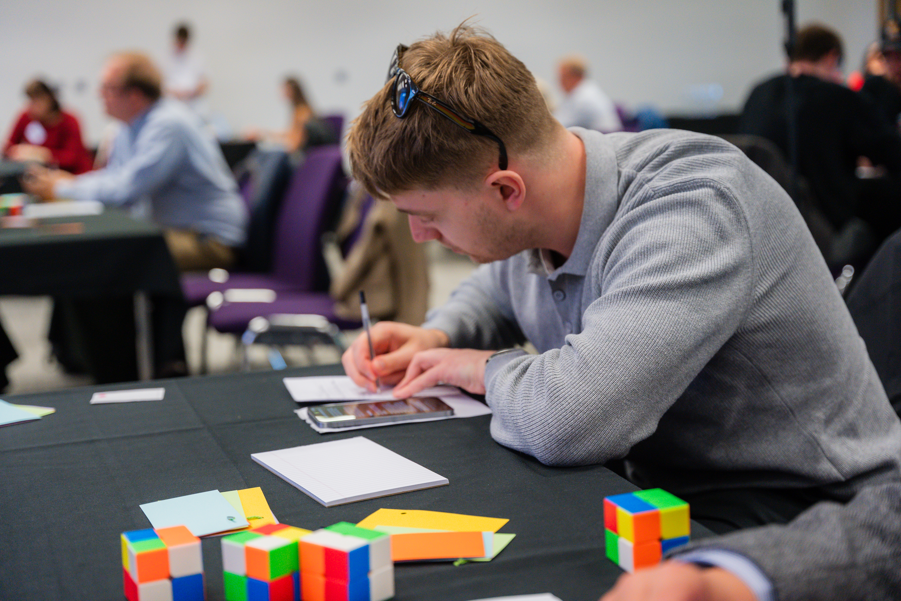 Participant concentrating on business simulation game with colorful blocks at table during team workshop