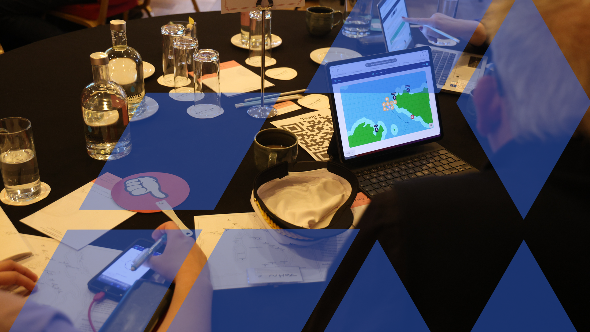 A team studies a strategy map on the simulation platform during a facilitated business simulation, overlaid with the Business Simulations brand motif