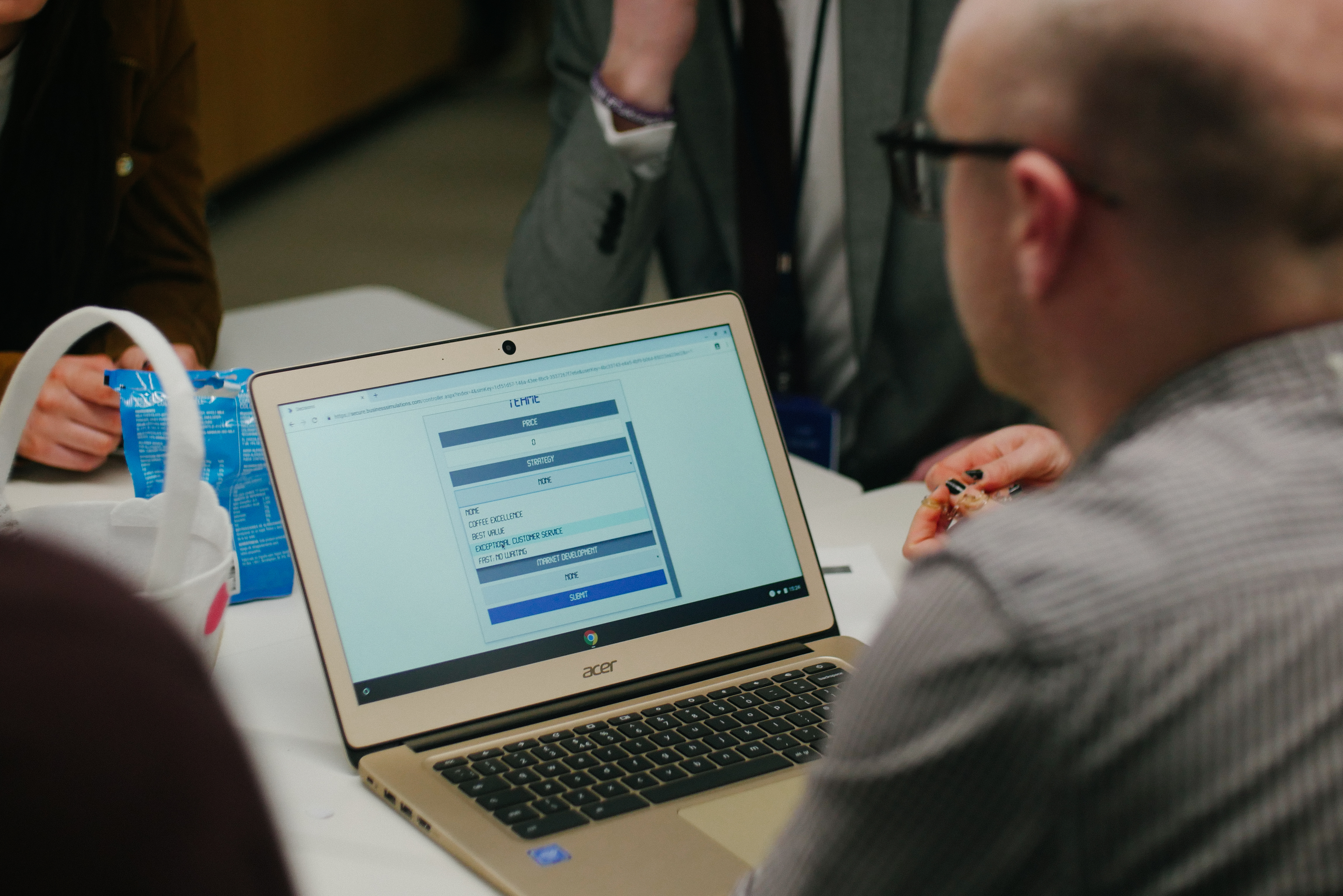A participant reviewing a live business simulation dashboard on a laptop during a facilitated team session