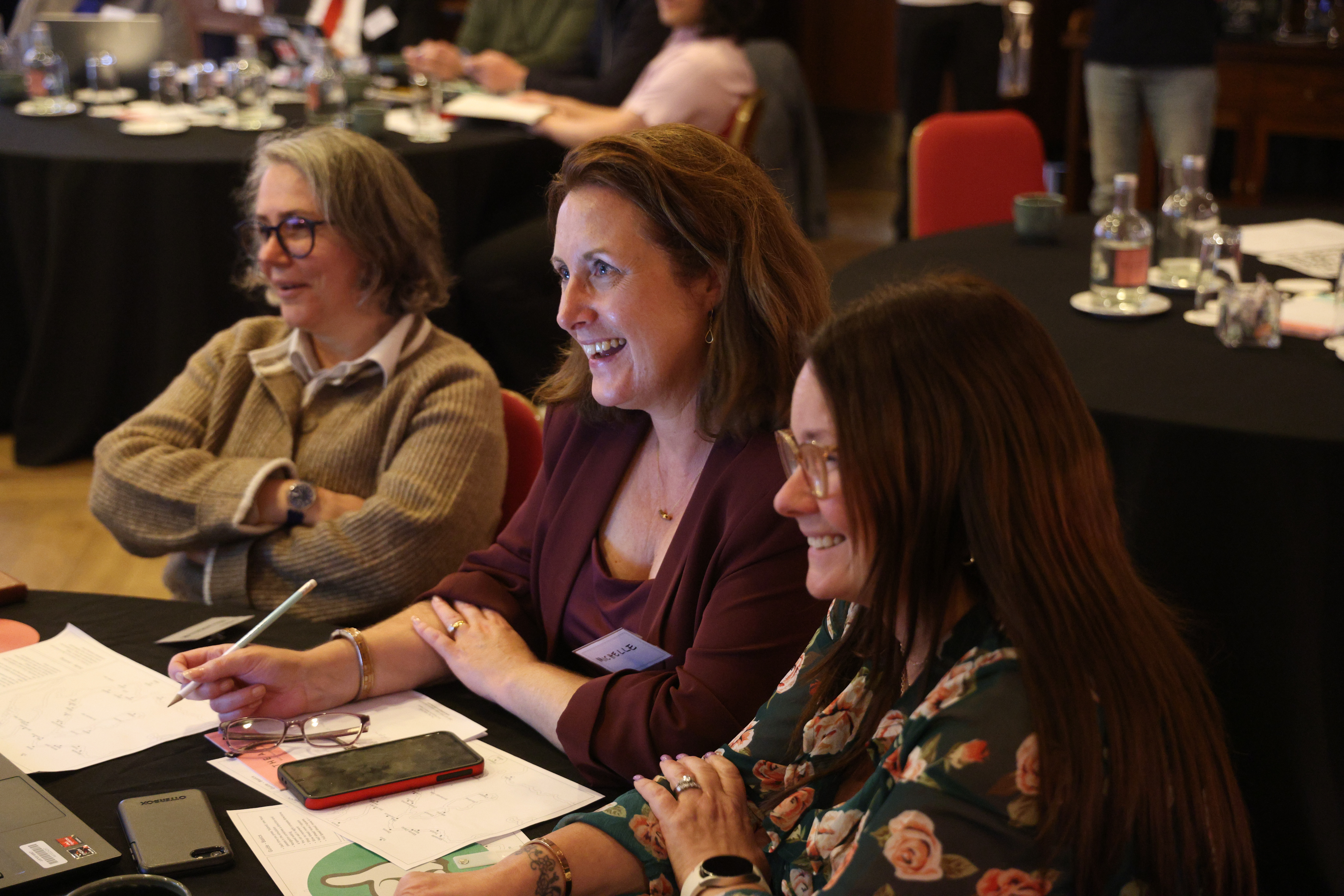 A team of participants engaged and smiling while working together during a facilitated business simulation