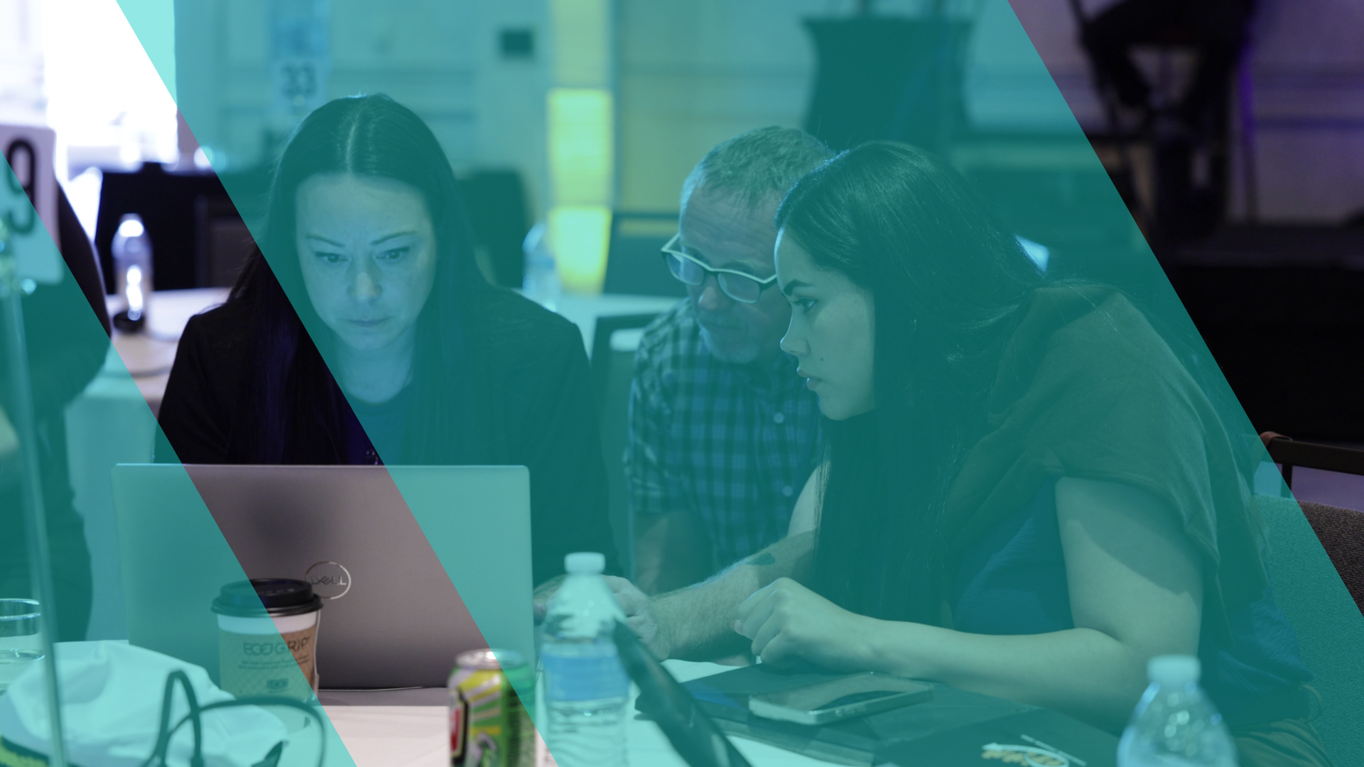Three participants concentrating on a laptop at a round table during a facilitated simulation, overlaid with a teal Business Simulations brand motif