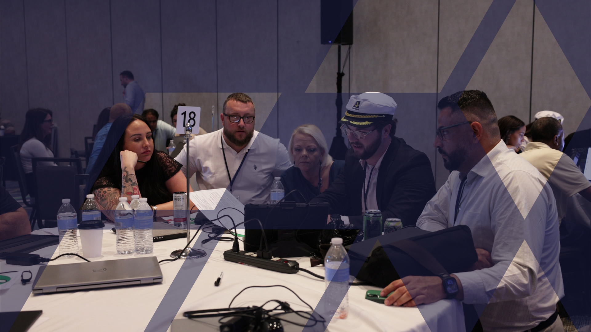 A team of participants working through a decision together at a round table, one wearing a captain's hat.