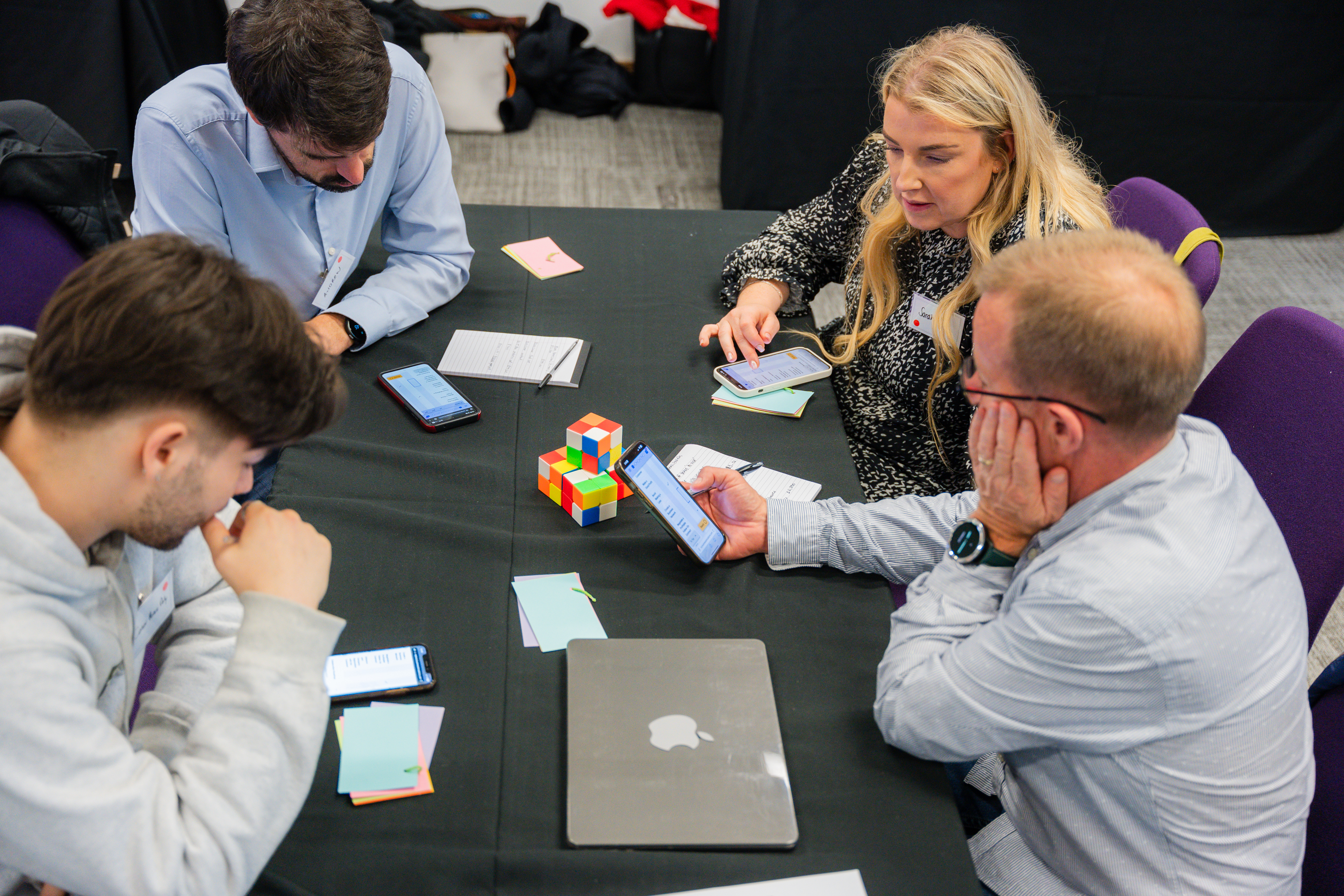Four participants in a simulation discussing at a table while looking at the simulation on a phone